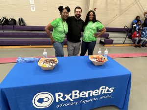 Three people standing in front of a table showcasing RxBenefits while emphasizing the importance of company culture.