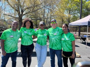 A group of people in green tie dye shirts showcasing their vibrant culture while posing for a photo.