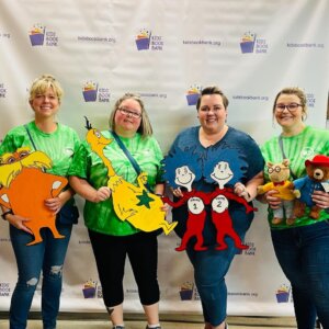 Four women posing with Dr. Seuss teddy bears.