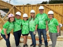 A group of people in green t-shirts representing culture, standing in front of a building.