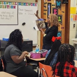 A teacher in a classroom fostering cultural understanding by reading to her students.