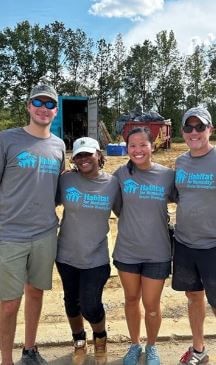 A culturally diverse group posing for a photo in their t-shirts.