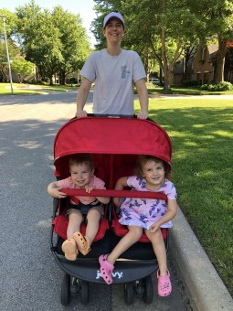 A suburban woman pushing two kids in a stroller
