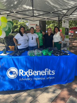 Five women of color standing behind a trade show table, representing RxBenefits' Palante Unidos initiative