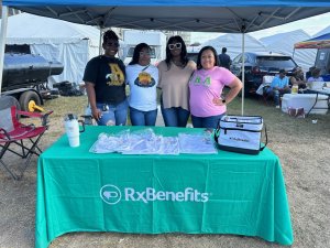 Four women of color standing behind a trade show table, representing RxBenefits' Black Advocate initiative